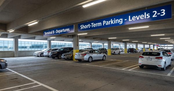 Airport parking garage with clear signage and vehicles in covered structure near terminal