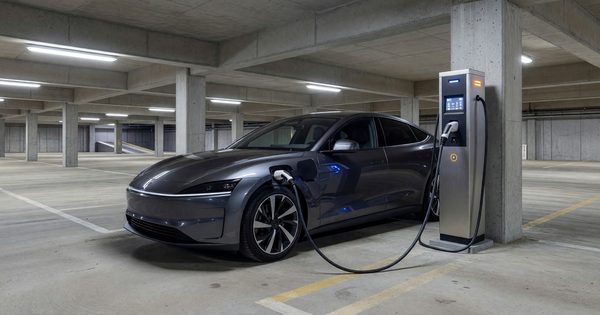 Electric vehicle plugged into charging station in covered parking garage