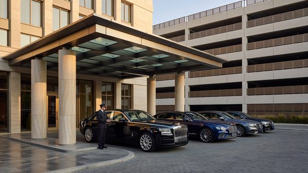 Hotel entrance with covered porte-cochère and parked cars visible in an adjacent structured garage