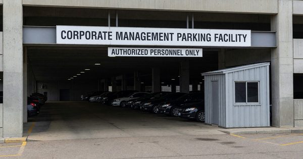 Parking garage exterior with corporate management signage at facility entrance