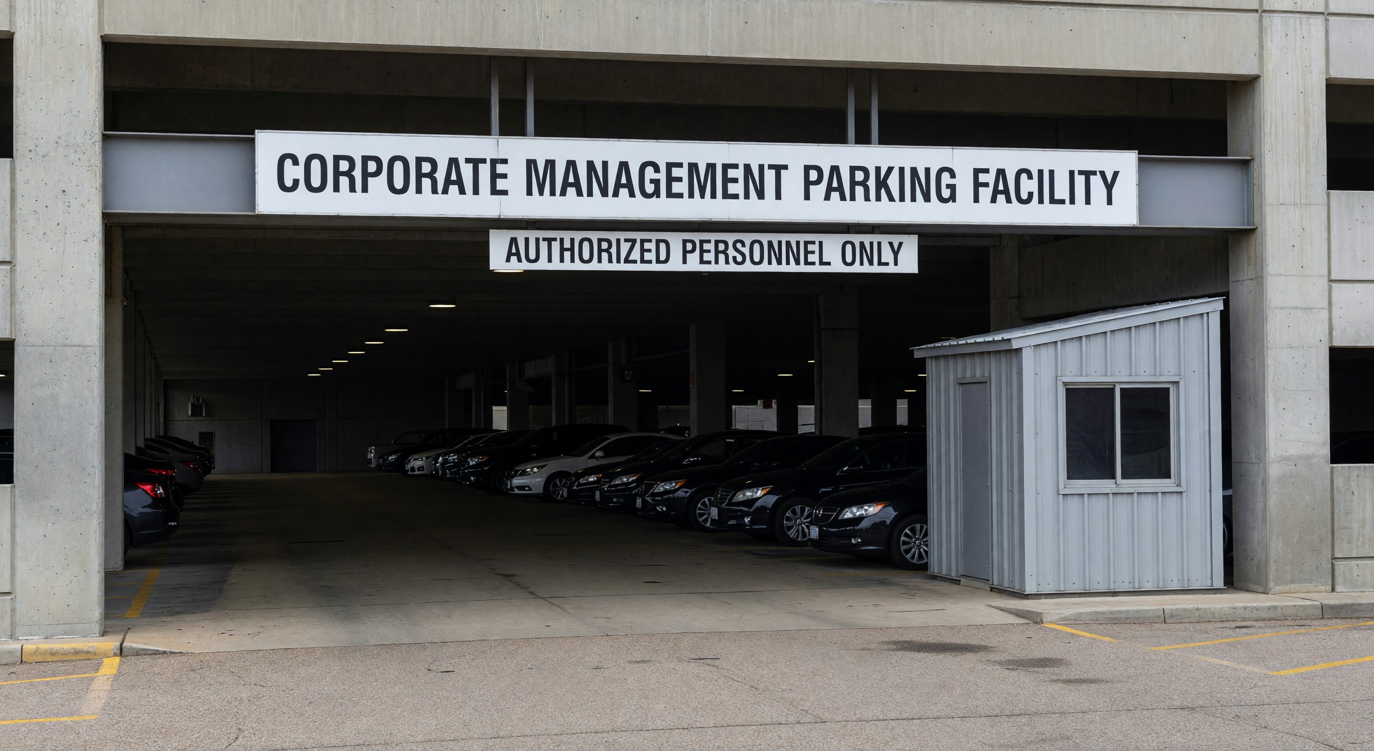 Parking garage exterior with corporate management signage at facility entrance